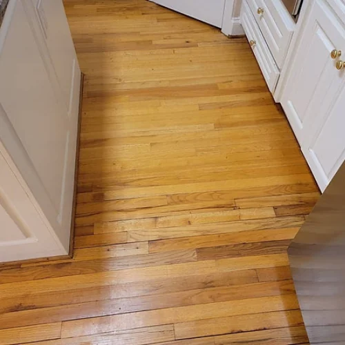 Oak strip hardwood floor in a kitchen after cleaning, grain showing through the finish