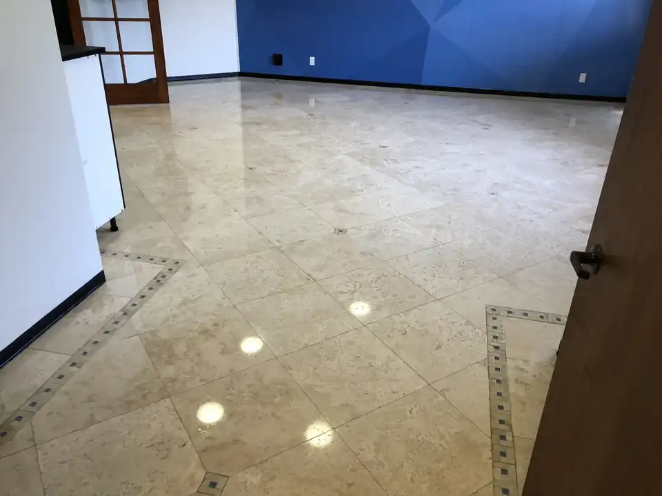 Polished cream stone floor with a dark inlay border reflecting the ceiling lights