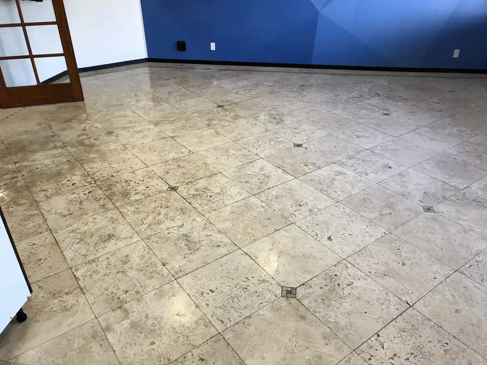 Polished cream stone entry floor with a dark inlay border, dull and marked before cleaning